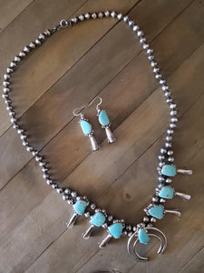 A Turquoise Squash Blossom Necklace adds a bold statement to any outfit. Like this Kingman Turquoise piece hand crafted by Navajo Artist Tatum  skeets.